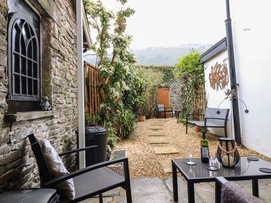 An outdoor patio area with chairs a table and plants at Siskin in Dinas Mawddwy near Dolgellau