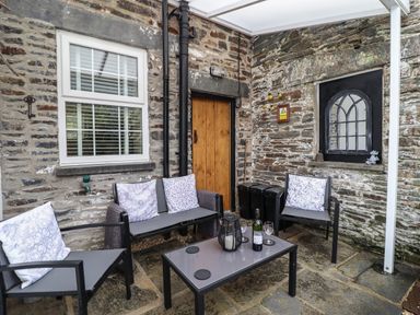 An outdoor seating area with chairs a small table a wooden door and stone walls at Siskin in Dinas Mawddwy near Dolgellau