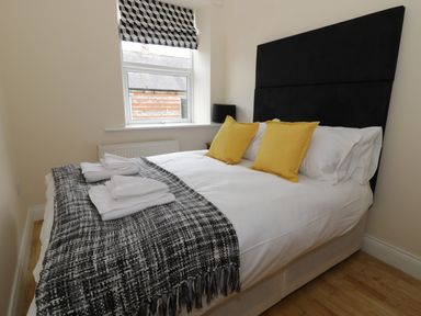 A bedroom with a double bed with yellow pillows and a black and white blanket at Dumbuie in Haltwhistle