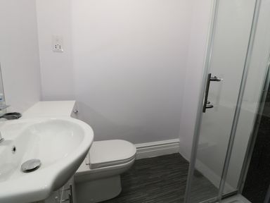 A bathroom with a sink toilet and glass shower door at Dumbuie in Haltwhistle