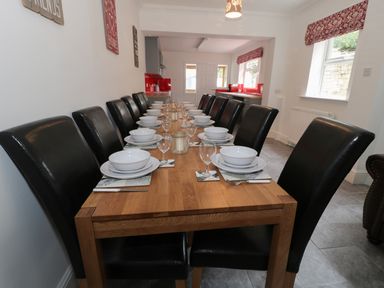 A dining room with a long wooden table set with bowls plates glasses and cutlery at Dumbuie in Haltwhistle