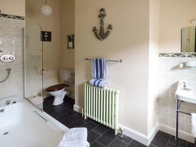 A bathroom with a bathtub toilet sink radiator and towels at Rhydlandgoed Stepaside near Saundersfoot