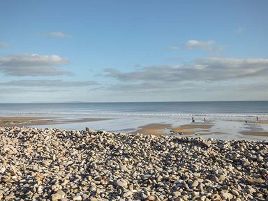 A rocky beach with sand and sea under a blue sky at Rhydlandgoed in Stepaside near Saundersfoot