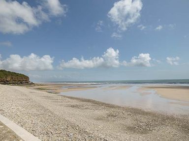 A beach with pebbles and sand near the water under a partly cloudy sky at Rhydlandgoed in Stepaside near Saundersfoot