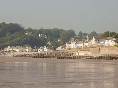 A coastal village with houses near a beach and a stone seawall at Rhydlandgoed Stepaside near Saundersfoot