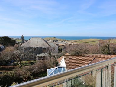 View of houses with tiled and slate roofs overlooking the sea and green fields at Sunset View in Porth