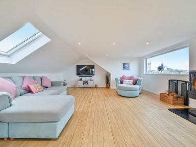 A living room with a sofa, television, and fireplace at Sunset View in Porth