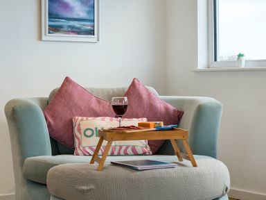 A living room with an armchair and a table tray at Sunset View in Porth