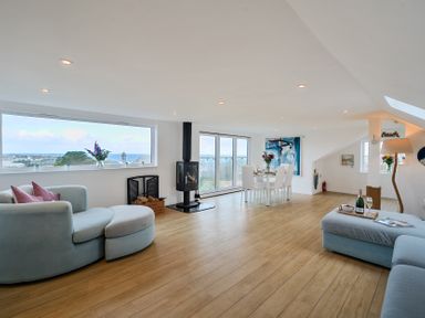 A living room with a dining area and large windows at Sunset View in Porth