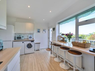 A kitchen with appliances and bar seating at Sunset View in Porth
