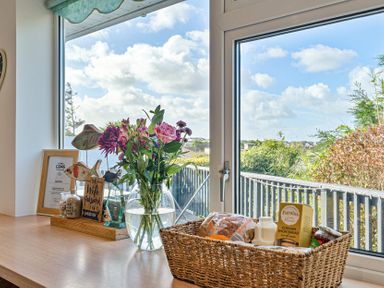 A kitchen with a window displaying flowers and a basket at Sunset View in Porth