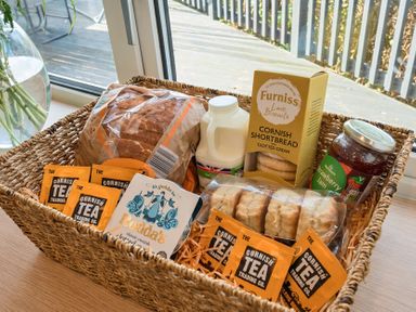 A basket containing bread, milk, shortbread, strawberry jam, and tea bags at Sunset View in Porth
