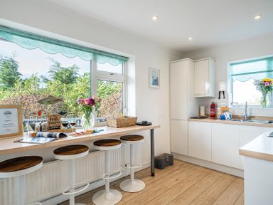A kitchen with a sink and bar stools at Sunset View in Porth