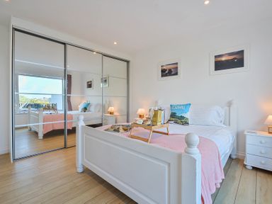 A bedroom with a bed and mirrored wardrobe at Sunset View in Porth