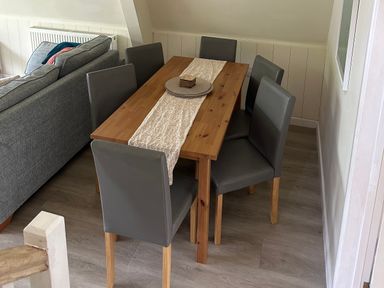 A dining room with a wooden table and grey chairs at Lodge 22, Bodmin Holiday Park, Cornwall in Lanivet