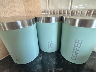 Three storage jars for sugar, tea, and coffee in a kitchen