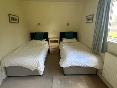 A bedroom with two single beds and a nightstand at Lodge 22, Bodmin Holiday Park, Cornwall, Lanivet