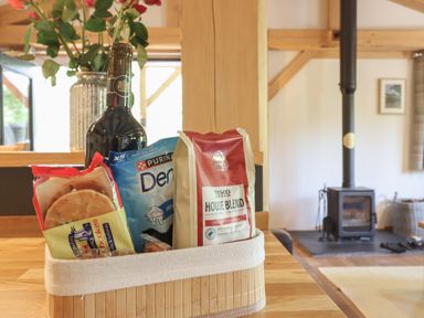 A kitchen with a basket of snacks and a wood stove at Lady Bagots Cabin in Ruthin