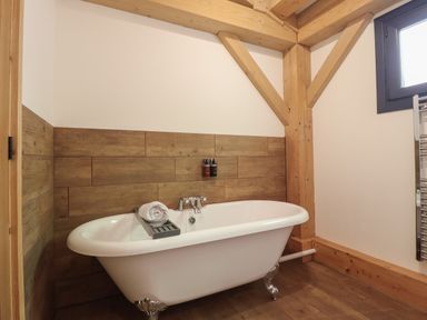 A bathroom with a bathtub and wooden beams at Lady Bagots Cabin in Ruthin