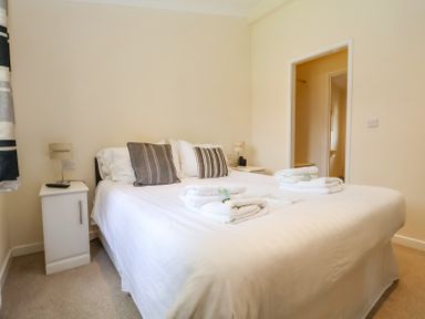 A bedroom with a bed with folded towels and pillows bedside tables and lamps at Callow Lodge 22 in Beaconsfield Holiday Park