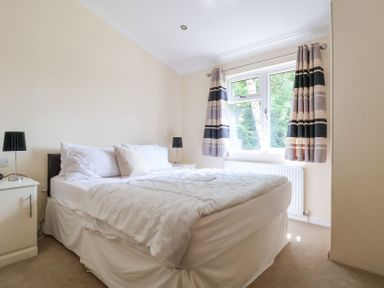 A bedroom with a double bed two bedside tables with lamps and a window with curtains at Callow Lodge 22 in Beaconsfield Holiday Park