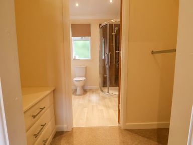 A view through a doorway into a bathroom with a toilet and a glass-enclosed shower at Callow Lodge 22 in Beaconsfield Holiday Park