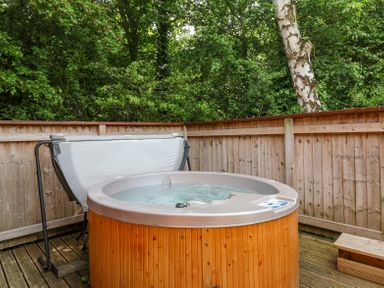 A wooden hot tub on a deck enclosed by a wooden fence with trees behind at Callow Lodge 22 in Beaconsfield Holiday Park