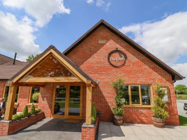 The exterior of a brick building with a wooden-framed glass entrance and potted plants at Callow Lodge 22 in Beaconsfield Holiday Park