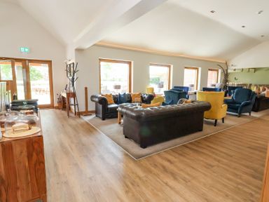 A lounge area with leather sofas armchairs and large windows at Callow Lodge 22 in Beaconsfield Holiday Park