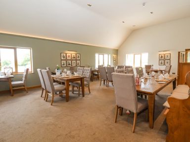 A dining room with wooden tables and upholstered chairs at Callow Lodge 22 in Beaconsfield Holiday Park