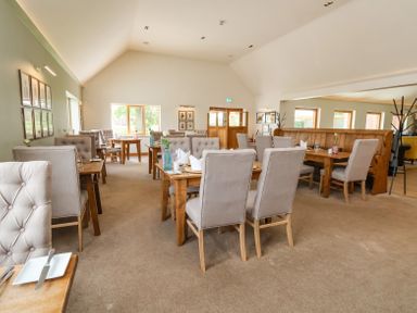 A dining room with wooden tables and upholstered chairs at Callow Lodge 22 in Beaconsfield Holiday Park