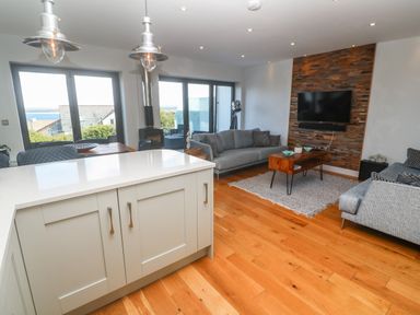 A living room with two grey sofas a wooden coffee table and a wall mounted television at Seafield in Carbis Bay near St Ives