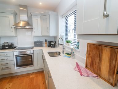 A kitchen with white countertops a stainless steel oven a toaster and a window with blinds at Seafield in Carbis Bay near St Ives