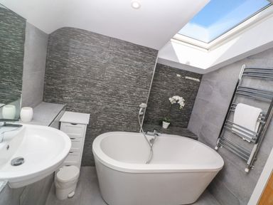A bathroom with a bathtub sink towel rack and skylight at Seafield in Carbis Bay near St Ives