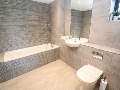 A bathroom with a bathtub sink toilet and a small plant on the window ledge at Seafield in Carbis Bay near St Ives
