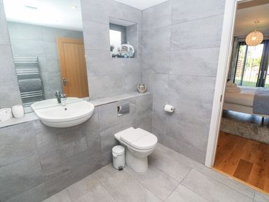 A bathroom with a wall-mounted sink a toilet and a small window at Seafield in Carbis Bay near St Ives