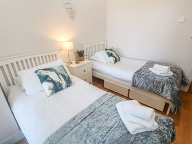 A bedroom with two single beds bedside table lamp and folded towels at Seafield in Carbis Bay near St Ives