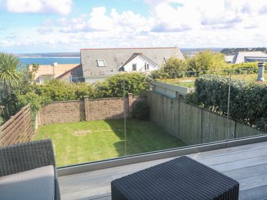 A glass balcony overlooking a backyard with grass and fences at Seafield in Carbis Bay near St Ives