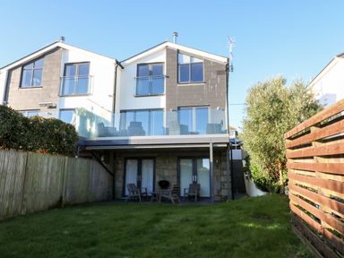 A two-story semi detached house with balconies and a grassy backyard at Seafield in Carbis Bay near St Ives