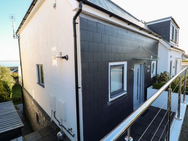 A modern exterior of a two-story house with a balcony and a view of the sea at Seafield in Carbis Bay near St Ives