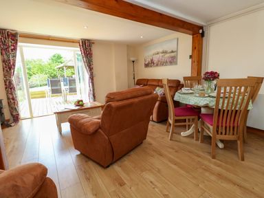 A living room with a dining area and a sliding door at Mallows Byre in Yetminster