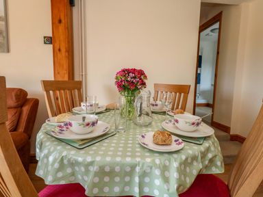 A dining room table set with dishes and flowers at Mallows Byre in Yetminster