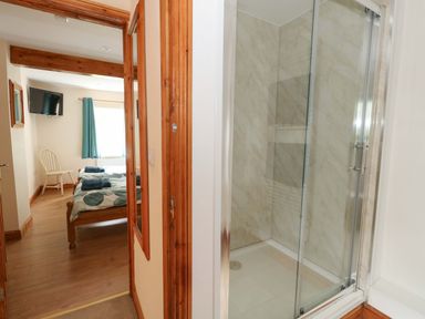 A shower and view of a bedroom with a bed and chair at Mallows Byre in Yetminster