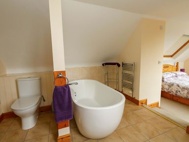 A bathroom with a bathtub and toilet at Mallows Byre in Yetminster