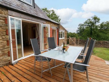 An outdoor dining area with a table and chairs at Mallows Byre in Yetminster