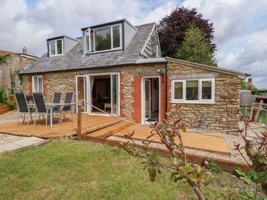 An outdoor space with a deck and seating at Mallows Byre in Yetminster