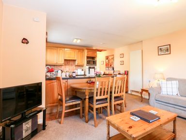 A living room with wooden dining table and chairs kitchen cabinets and sofa at The Ramblers Annex in Mattishall