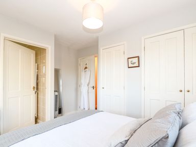A bedroom with bed pillows doors and a bathrobe hanging on a door at The Ramblers Annex in Mattishall