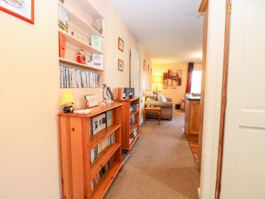 A hallway with wooden bookshelves and a seating area with sofas and lamps at The Ramblers' Annex in Mattishall