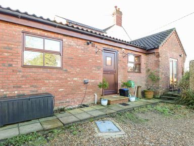 An exterior view of a brick building with two windows a door and outdoor plants at The Ramblers Annex in Mattishall